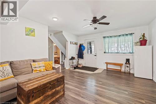 Living area featuring wood-finish flooring, a ceiling fan with integrated lighting, and a white entry door with decorative glass - 54 E Chestnut Street E, St. Catharines, ON - Indoor Photo Showing Living Room