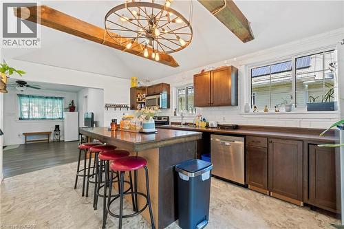 Kitchen featuring a central island with countertop seating, wood-finish cabinetry, stainless steel appliances, and a tile backsplash - 54 E Chestnut Street E, St. Catharines, ON - Indoor Photo Showing Kitchen