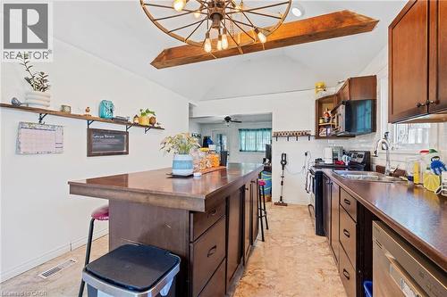 Kitchen featuring wood cabinetry, coordinating countertops, an integrated dishwasher, and a stainless steel sink with a gooseneck faucet - 54 E Chestnut Street E, St. Catharines, ON - Indoor Photo Showing Kitchen