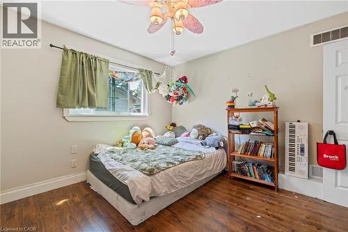 Room with wood-finish flooring, a window with green drapes, and a ceiling fan light fixture - 54 E Chestnut Street E, St. Catharines, ON - Indoor Photo Showing Bedroom