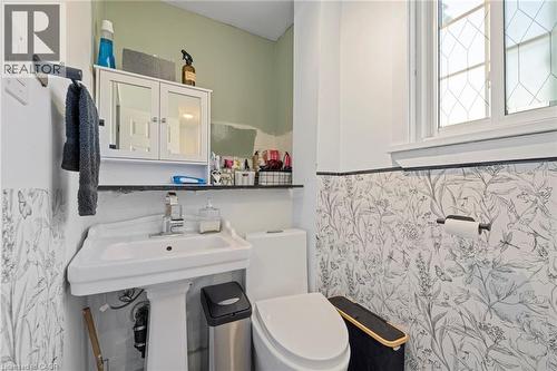 Bathroom featuring a pedestal sink, wall-mounted mirror cabinet, and a window with decorative muntins - 54 E Chestnut Street E, St. Catharines, ON - Indoor