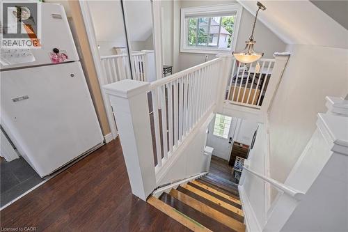 Multi-level interior featuring wood-finish flooring, white painted railings, and a built-in light fixture - 54 E Chestnut Street E, St. Catharines, ON - Indoor Photo Showing Other Room