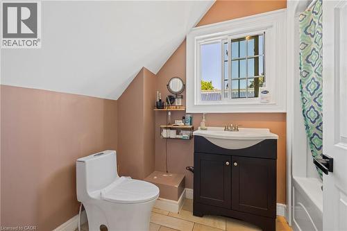 Bathroom featuring a white toilet, dark wood-finish vanity with an integrated sink, and a white-framed window - 54 E Chestnut Street E, St. Catharines, ON - Indoor Photo Showing Bathroom