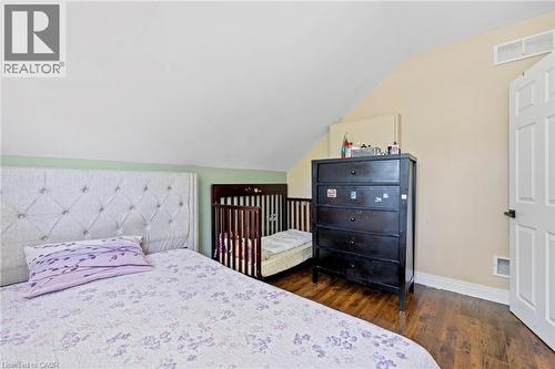 Sloped ceiling room featuring wood-finish flooring, light-colored walls, and a multi-paneled white door - 54 E Chestnut Street E, St. Catharines, ON - Indoor Photo Showing Bedroom