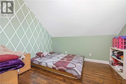 Bedroom featuring a distinctive accent wall with a geometric pattern, warm wood-finish flooring, and sloped ceiling - 54 E Chestnut Street E, St. Catharines, ON - Indoor Photo Showing Bedroom