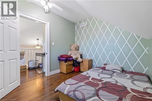 Bedroom featuring wood-finish flooring, a ceiling fan, and an accent wall with a geometric pattern - 54 E Chestnut Street E, St. Catharines, ON - Indoor Photo Showing Bedroom