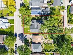 Aerial perspective showcasing a residential property with a multi-story home, a paved driveway, and extensive mature trees - 