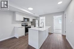 Kitchen featuring appliances with stainless steel finishes, white cabinets, a center island with sink, and dark wood finished floors - 