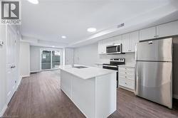 Kitchen featuring appliances with stainless steel finishes, white cabinetry, dark wood finished floors, and recessed lighting - 