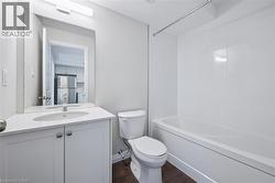 Full bath with shower / bathtub combination, vanity, and dark wood-style floors - 