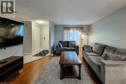 Open-concept living area featuring wood-finish flooring, light-toned wall paint, and a front entry with tile flooring - 