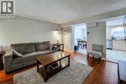 Living area featuring wood-finish flooring, light grey wall paint, and recessed ceiling lighting - 