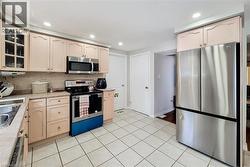 Kitchen featuring light-toned cabinetry, stainless steel appliances, tile flooring, and recessed lighting - 