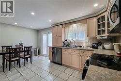 Kitchen featuring tile flooring, light-colored cabinetry with display upper cabinets, a window above the sink, and a tile backsplash - 