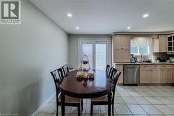 Kitchen featuring light-toned cabinetry, stainless steel dishwasher, tile flooring, recessed ceiling lighting, and a sliding glass door - 