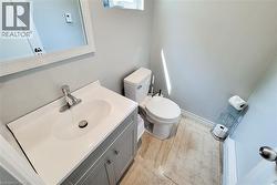Powder room featuring a single vanity with a white countertop and oval sink, a contemporary silver-tone faucet, a decorative framed mirror, and a modern toilet - 