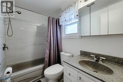 Bathroom featuring a built-in tub with a wall-mounted shower head, white tiled surround, and a single window - 