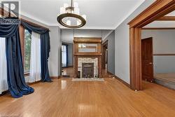 Hardwood flooring throughout featuring a decorative brick fireplace with an ornate wood mantel and a bay window - 