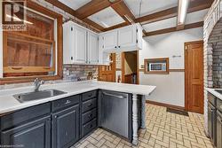 Kitchen featuring white upper cabinetry, dark lower cabinetry, and a stainless steel sink - 