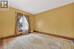 Room featuring a single window with wood trim, a built-in baseboard heater, and a patterned area rug covering wood-finish flooring - 