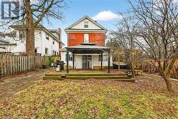 Rear exterior featuring a brick facade with white siding, ground-level patio with steps, and a black metal gazebo - 