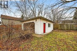 Detached garage with white siding, a red side door, and a single window - 