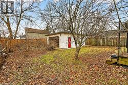 Detached garage with white siding and red entry door - 