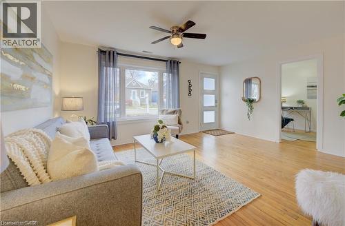 Bright living area featuring wood-finish flooring, a ceiling fan with integrated lighting, and a large window - 73 East 33Rd Street, Hamilton, ON 