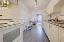 Galley-style kitchen featuring white cabinetry, a double basin stainless steel sink, a white electric range, and wood-finish flooring - 73 East 33Rd Street, Hamilton, ON 