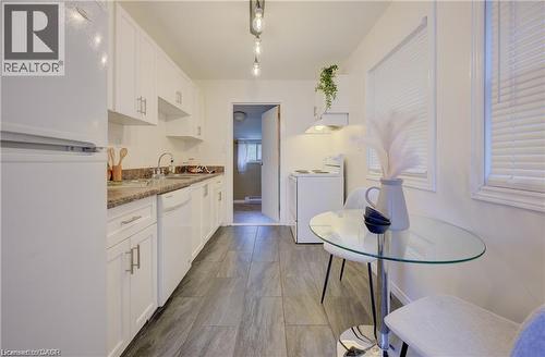 Galley kitchen featuring white cabinetry, stone-look countertops, and wood-finish flooring - 73 East 33Rd Street, Hamilton, ON 
