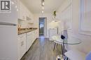 Galley kitchen featuring white cabinetry, stone-look countertops, and wood-finish flooring - 73 East 33Rd Street, Hamilton, ON 