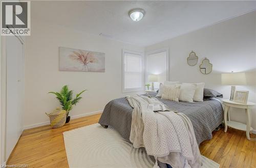Bedroom featuring polished hardwood flooring, white walls, and a built-in closet with white bifold doors - 73 East 33Rd Street, Hamilton, ON 