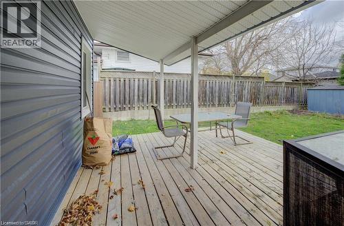 Expansive wooden deck with a covered patio area, featuring a slatted privacy fence, green lawn space, and an exterior storage shed - 73 East 33Rd Street, Hamilton, ON 