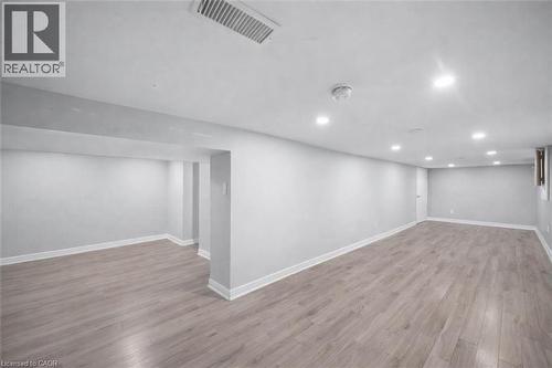 Spacious finished area featuring wood-finish flooring, recessed lighting, and crisp white trim - 106 Lottridge Street, Hamilton, ON 