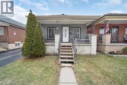 Grey exterior with white trim, featuring a covered porch with decorative railing and a white entry door - 