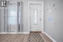 Entryway featuring a white paneled door with frosted glass insert, light wood-finish flooring, and white baseboards - 106 Lottridge Street, Hamilton, ON 