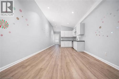 Expansive open-concept living area featuring wood-finish flooring, recessed lighting, and a modern kitchen with white cabinetry and dark countertops - 106 Lottridge Street, Hamilton, ON 