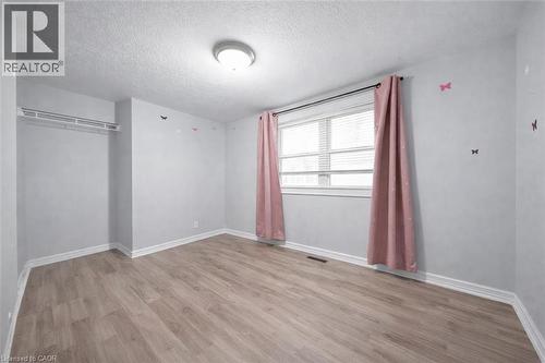 Light-filled room featuring wood-finish flooring, a double window with blinds, and white baseboards - 106 Lottridge Street, Hamilton, ON 