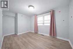 Light-filled room featuring wood-finish flooring, a double window with blinds, and white baseboards - 