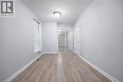 Spacious room with wood-finish flooring, white baseboards, and light gray walls - 