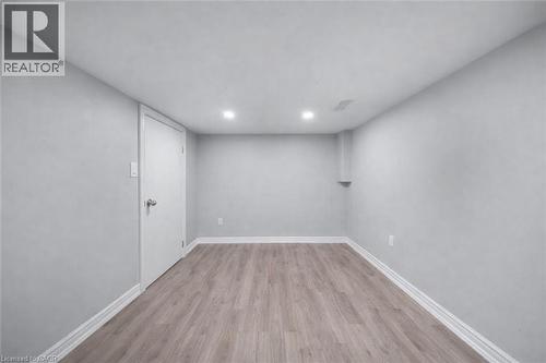 Bright room featuring light wood-finish flooring, recessed ceiling lighting, and crisp white baseboards - 106 Lottridge Street, Hamilton, ON 