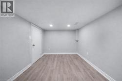 Bright room featuring light wood-finish flooring, recessed ceiling lighting, and crisp white baseboards - 