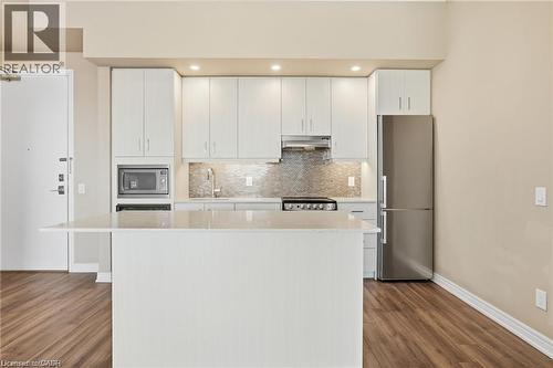 Kitchen featuring a white island, light cabinetry, stainless steel appliances, and wood-finish flooring - 40 Esplanade Lane Unit# 614, Grimsby, ON 