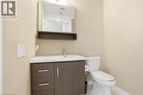 Bathroom featuring a dark wood-finish vanity with chrome hardware, an integrated sink, and a wall-mounted mirror with an integrated shelf - 40 Esplanade Lane Unit# 614, Grimsby, ON 
