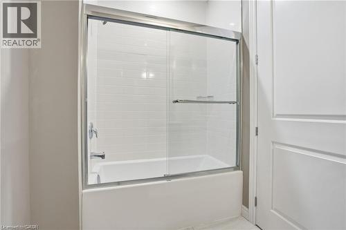 White bathtub and shower combination featuring subway tile surround, chrome fixtures, and a sliding glass enclosure - 40 Esplanade Lane Unit# 614, Grimsby, ON 
