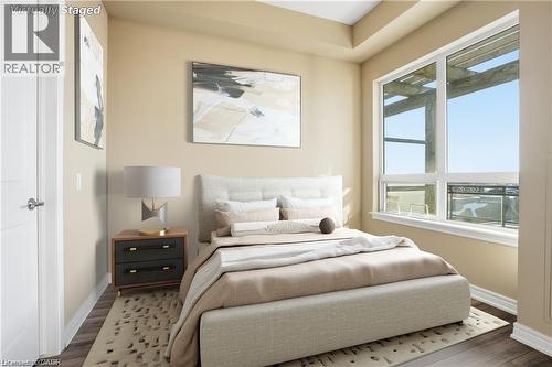 Hardwood-style flooring and light-toned walls define this bedroom, featuring a large window with white framing - 40 Esplanade Lane Unit# 614, Grimsby, ON 