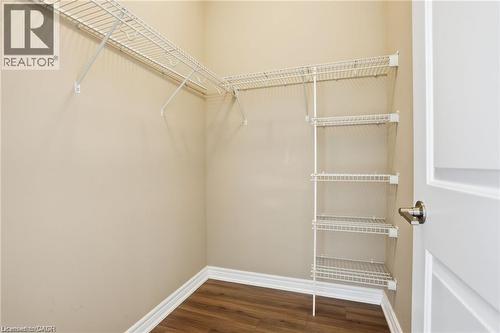 Walk-in closet featuring organized wire shelving, perimeter hanging rods, wood-finish flooring, and light neutral wall paint - 40 Esplanade Lane Unit# 614, Grimsby, ON 