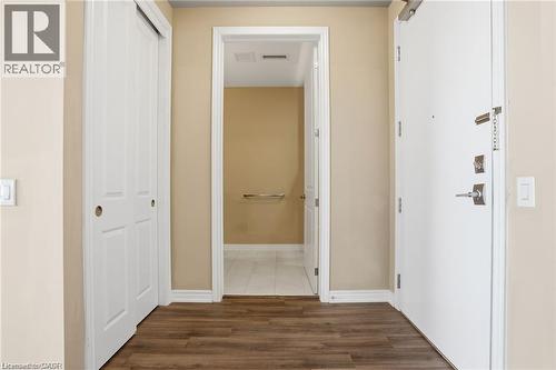 Entryway with wood-finish flooring, a white paneled closet door, and a solid white entrance door with modern hardware - 40 Esplanade Lane Unit# 614, Grimsby, ON 