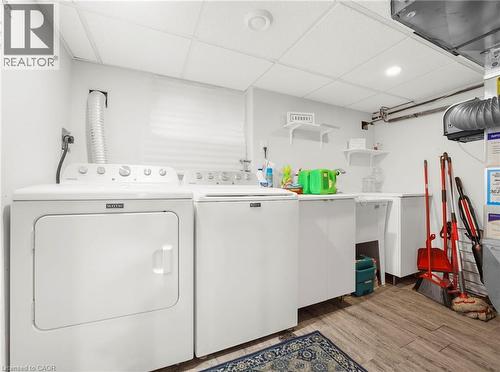 Dedicated laundry area featuring wood-finish flooring, white cabinetry, and built-in shelving - 420 Waverly Street, Hamilton, ON 