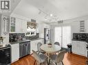 Kitchen featuring white cabinetry, wood-finish flooring, a mosaic tile backsplash, stainless steel appliances, and a glass-paneled exterior door. Some virtual staging - 420 Waverly Street, Hamilton, ON 
